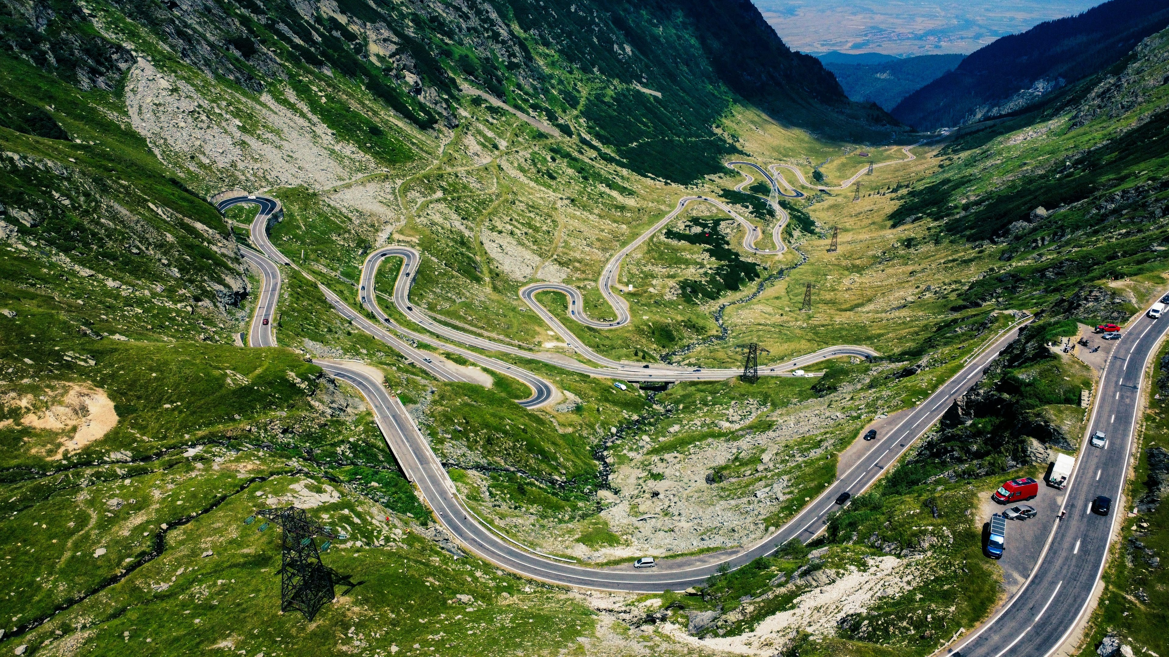 Aerial view of a winding mountain road through lush green valleys